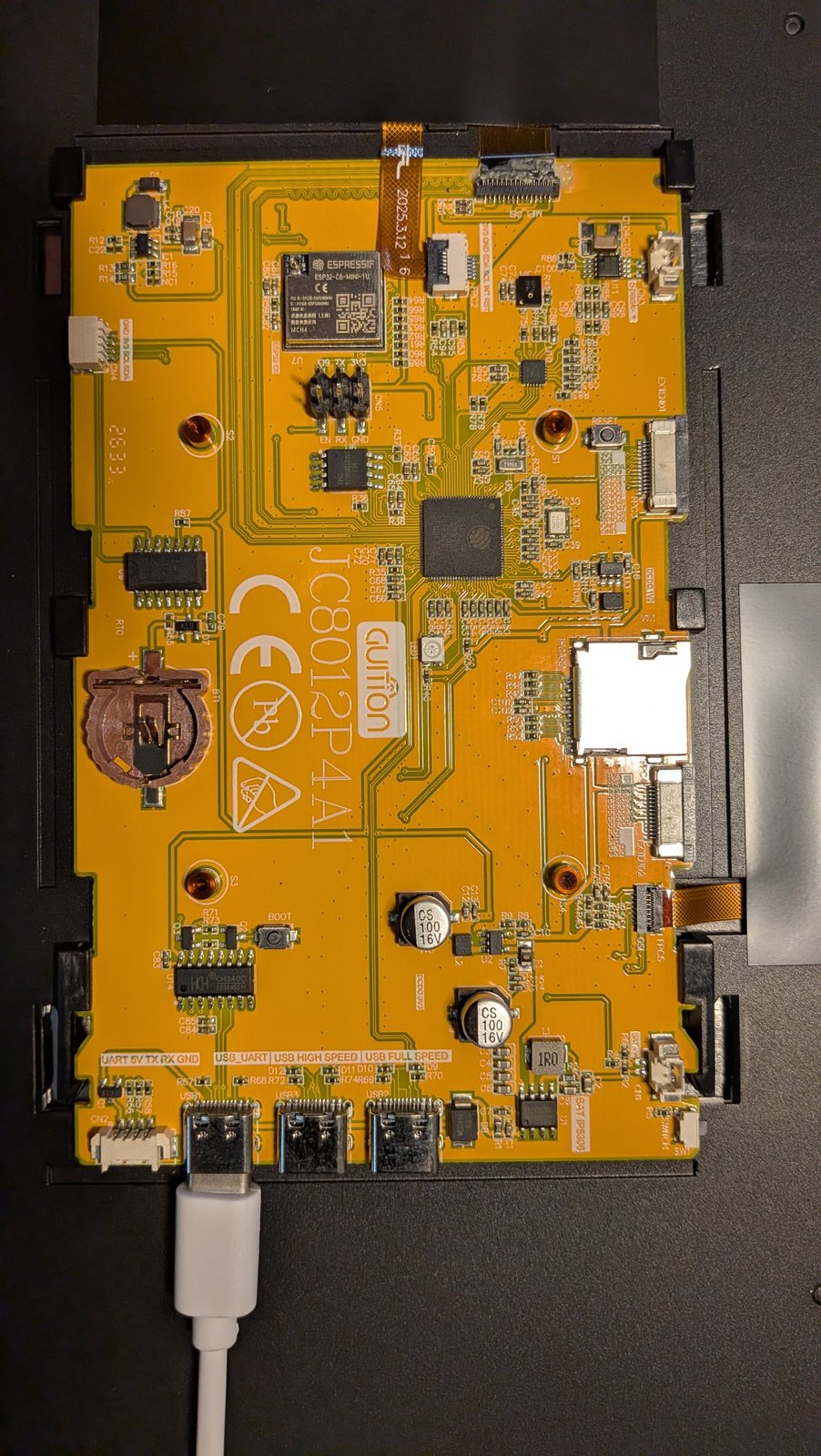 JC8012P4A1 board with the back cover removed, a USB cable plugged into the left USB-C port